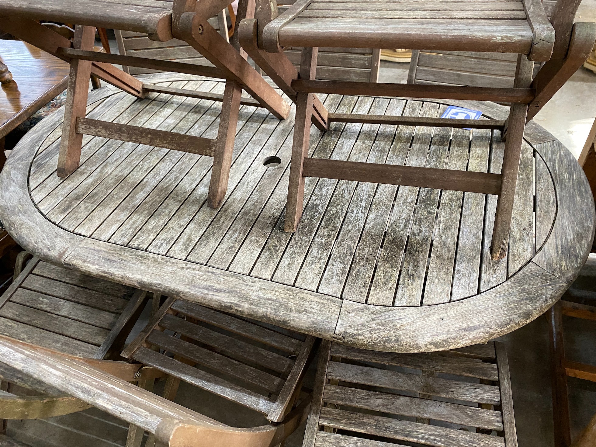 A weathered teak folding oval garden table, length 150cm, depth 91cm, height 74cm together with eight assorted chairs (2 carvers, 6 singles) *Please note the sale commences at 9am.